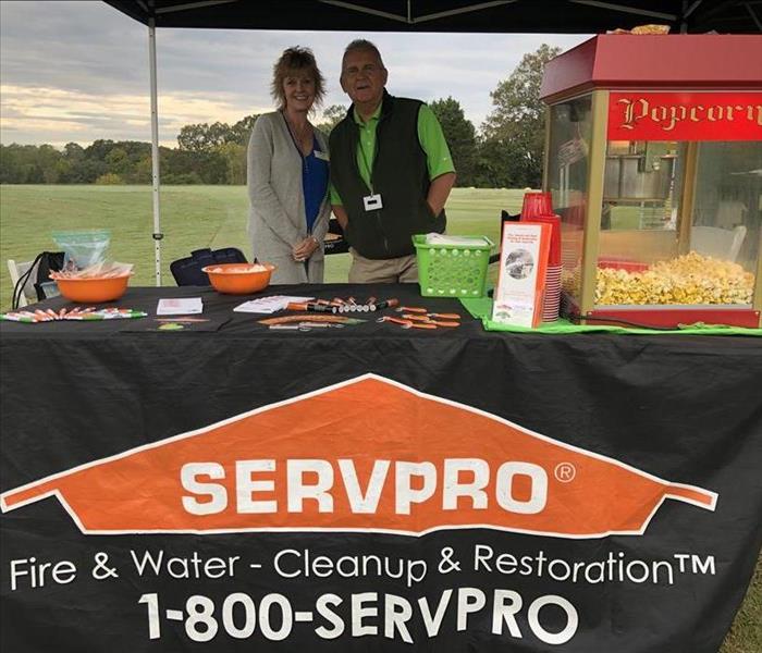 Two SERVPRO employees posing under a tent on golf greens