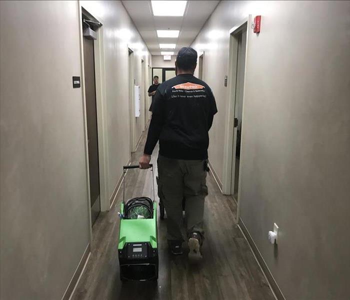SERVPRO employee dragging green machine down a hallway