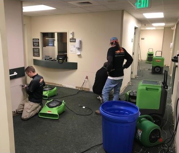 Three SERVPRO employees working in a hall full of green SERVPRO equipment