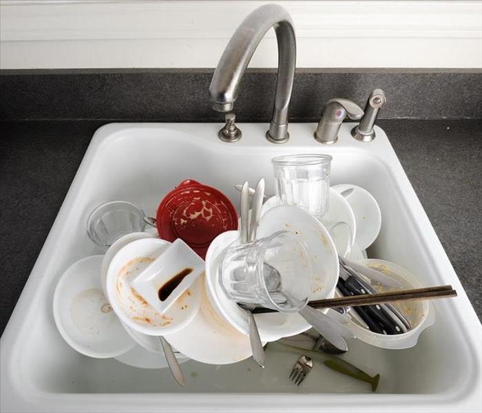 Dirty bowls, plates and silverware in a white sink