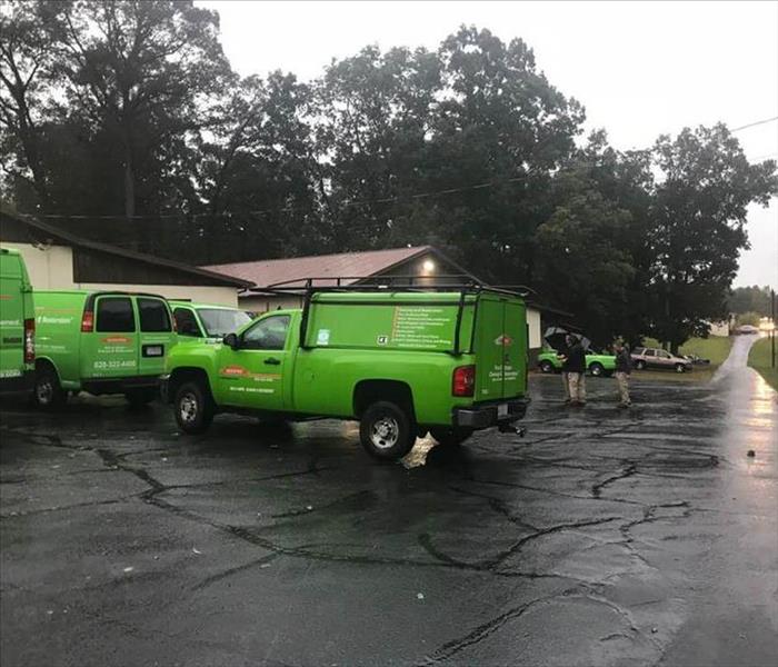 Green SERVPRO vehicles in a parking lot on a rainy morning