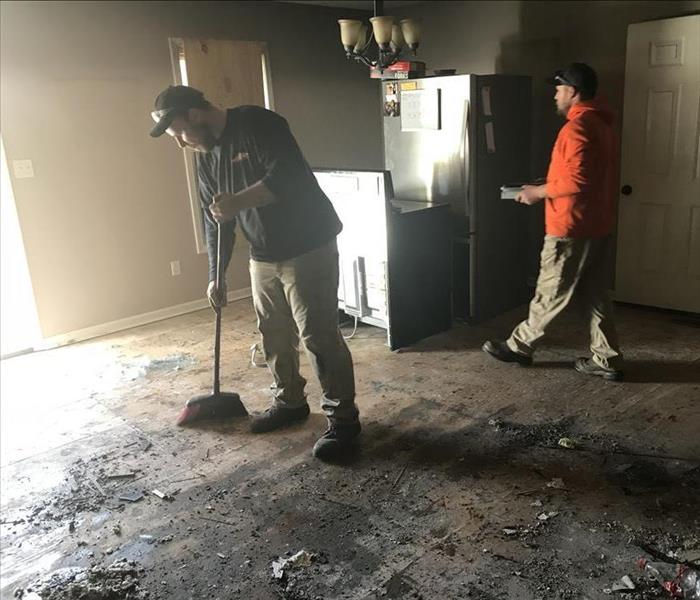 Two SERVPRO employees clean up soot and debris in a fire-damaged home